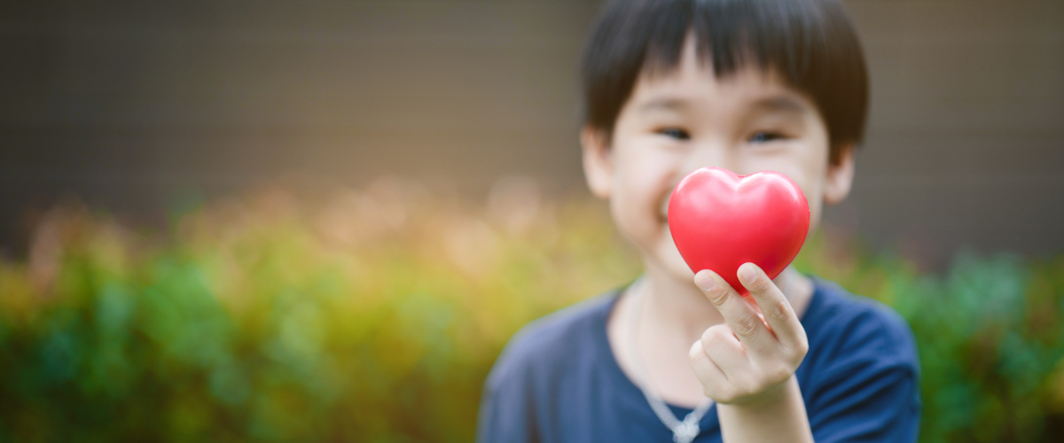 A Boy Holding A Heart Symbol