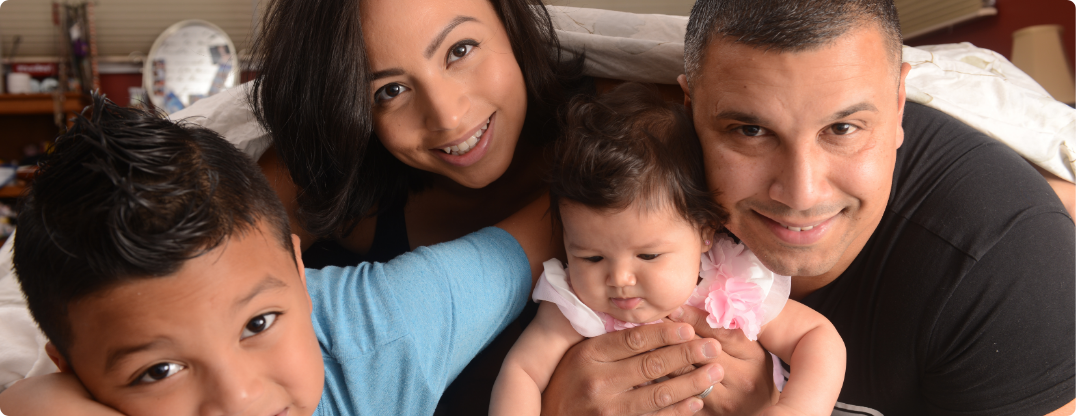mother and father hugging their son and infant daughter